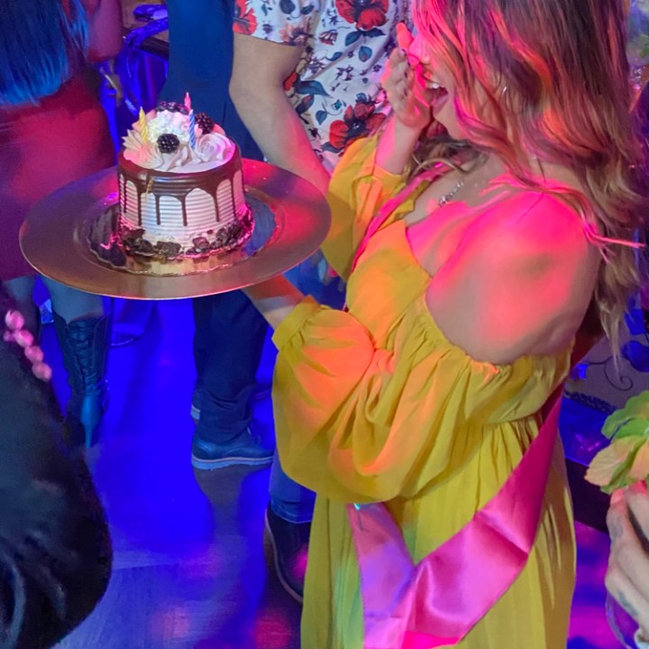 a little girl standing in front of a birthday cake