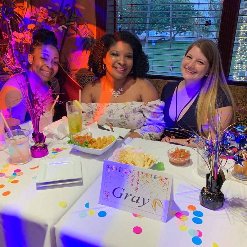 a group of people sitting at a table with a cake